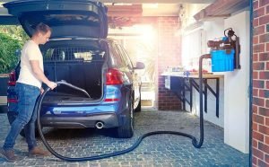 Homme aspirant le coffre d’un SUV avec un aspirateur mural Vacmaster monté dans un garage