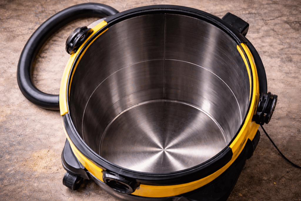 Aspirateur de chantier sans sac vu de dessus avec cuve métallique vide et intérieur propre.